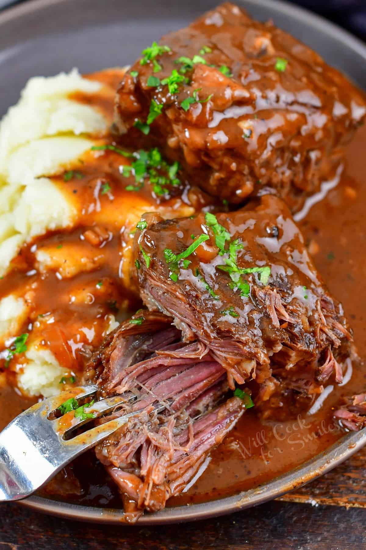 pulling apart short rib meat on a plate with a fork