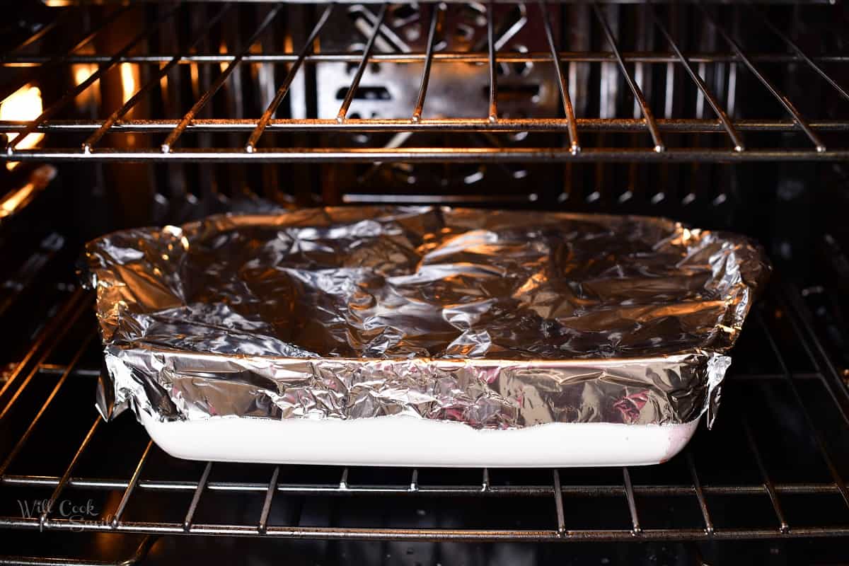 baking dish covered with aluminum foil in the oven.