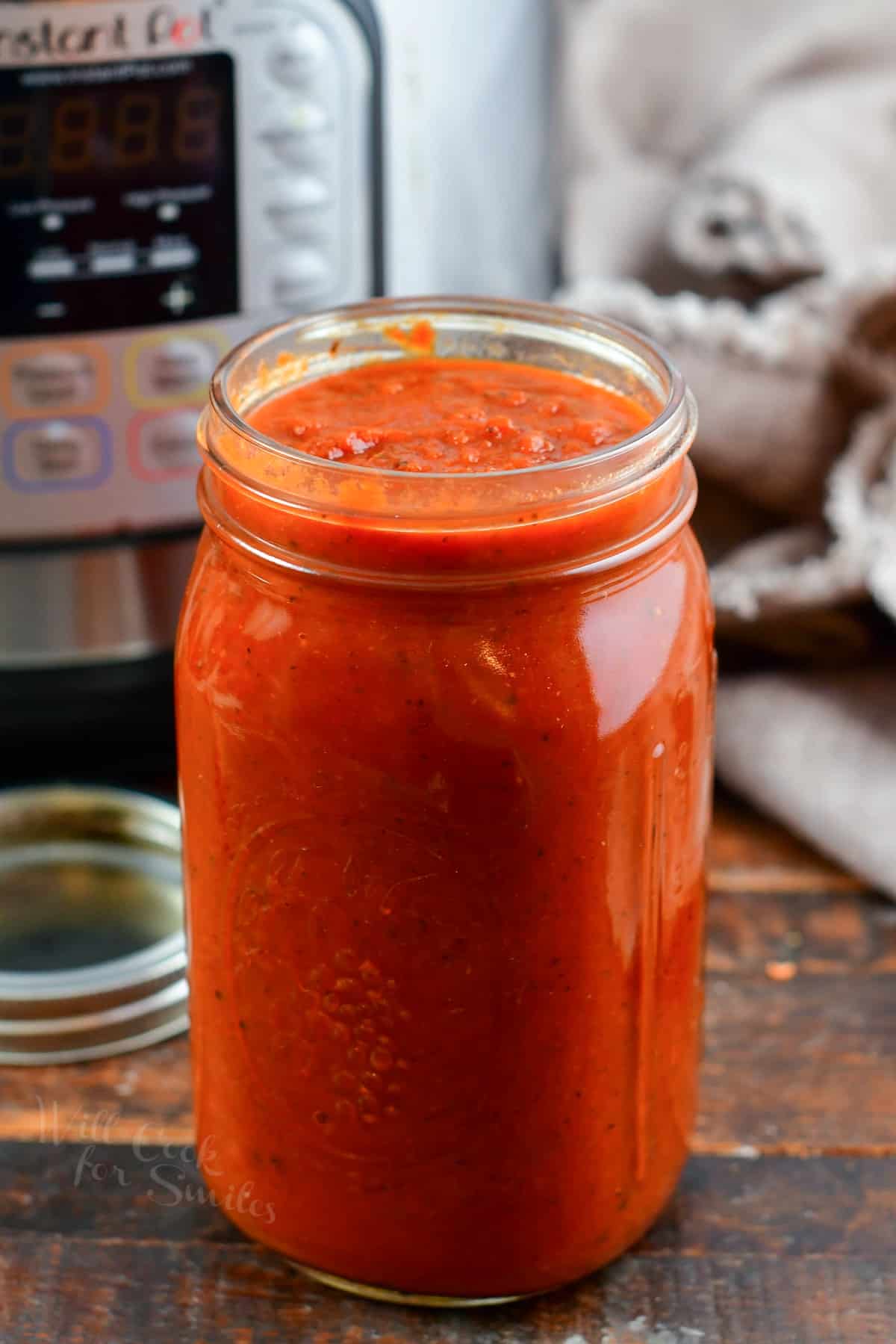 Spaghetti sauce in the glass jar next to Instant Pot