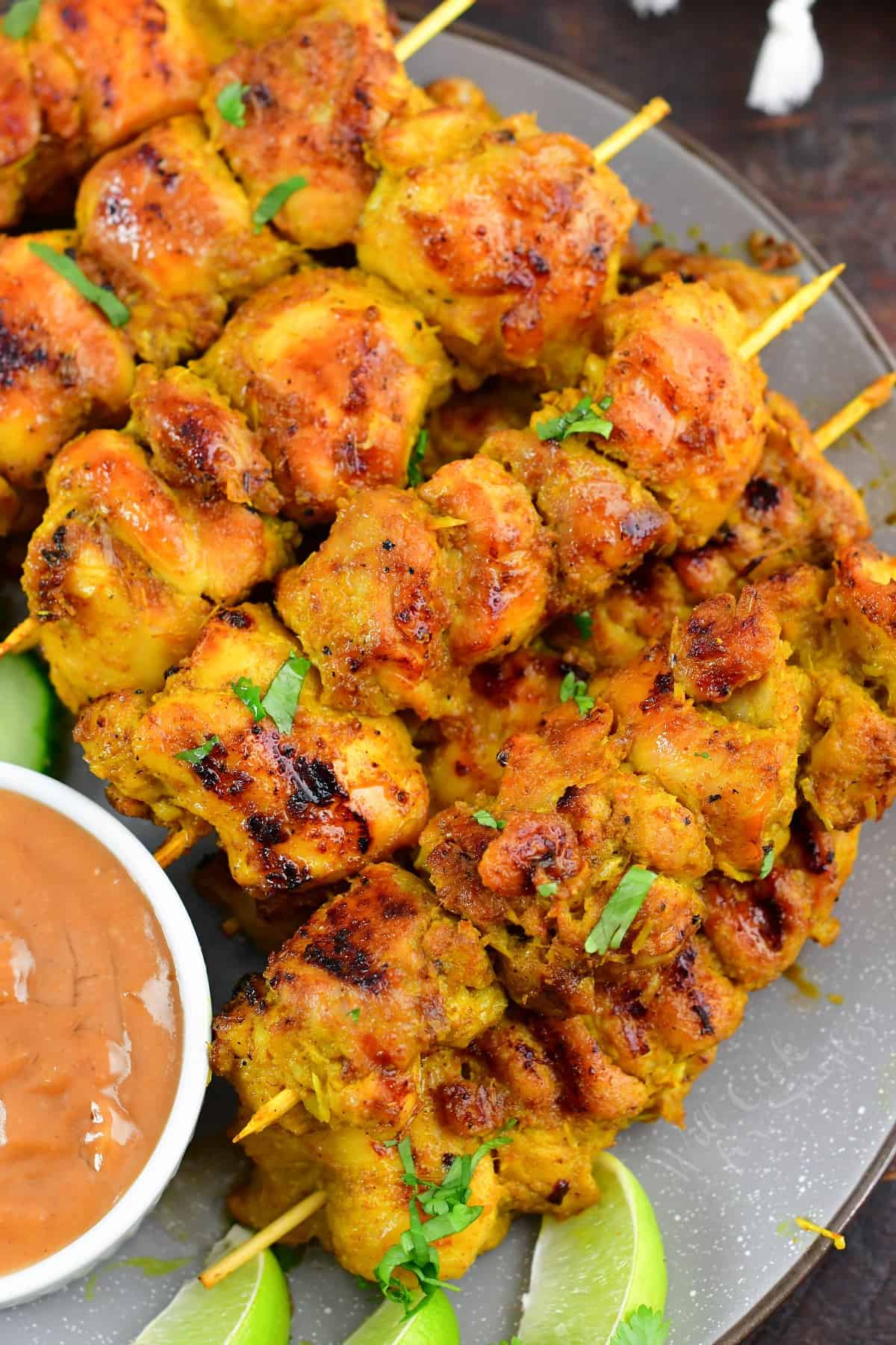 closeup of several skewers of chicken satay stacked