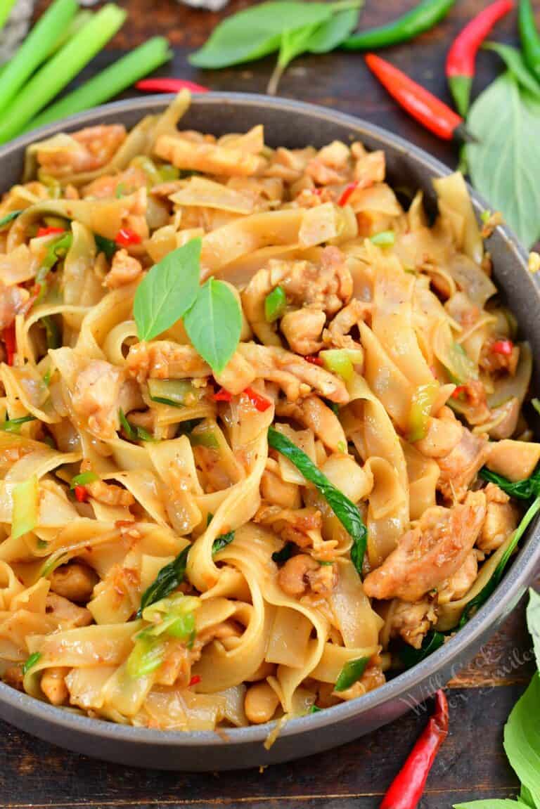 top view of drunken noodles in a bowl with veggies around