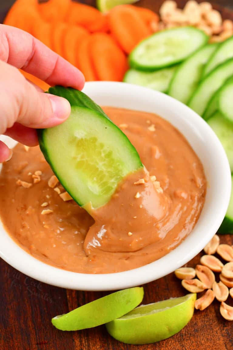 dipping cucumber into the peanut sauce