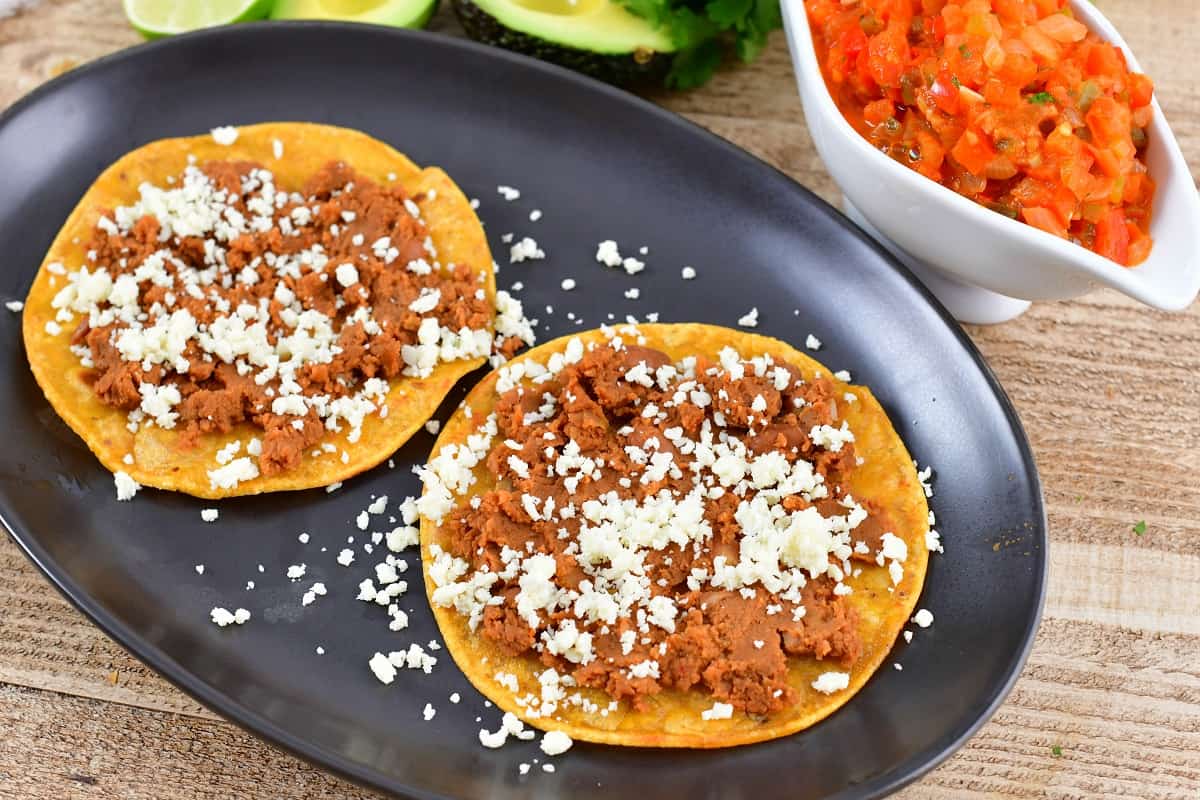 tortillas topped refried beans and queso fresco