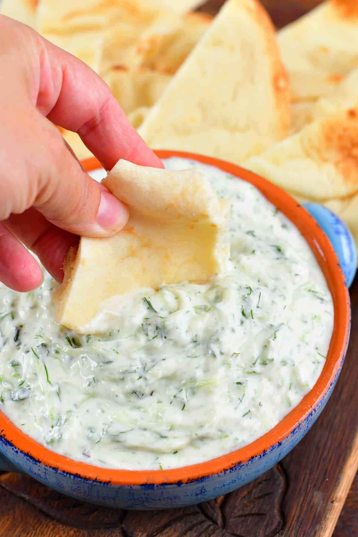 dipping into the tzatziki sauce with pita