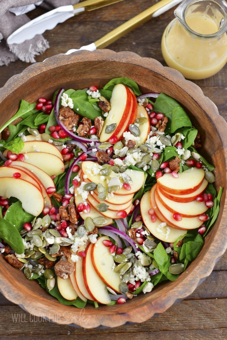 top view of apple salad in wooden bowl and dressing.