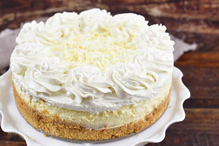 closeup whole vanilla cheesecake with whipped cream.