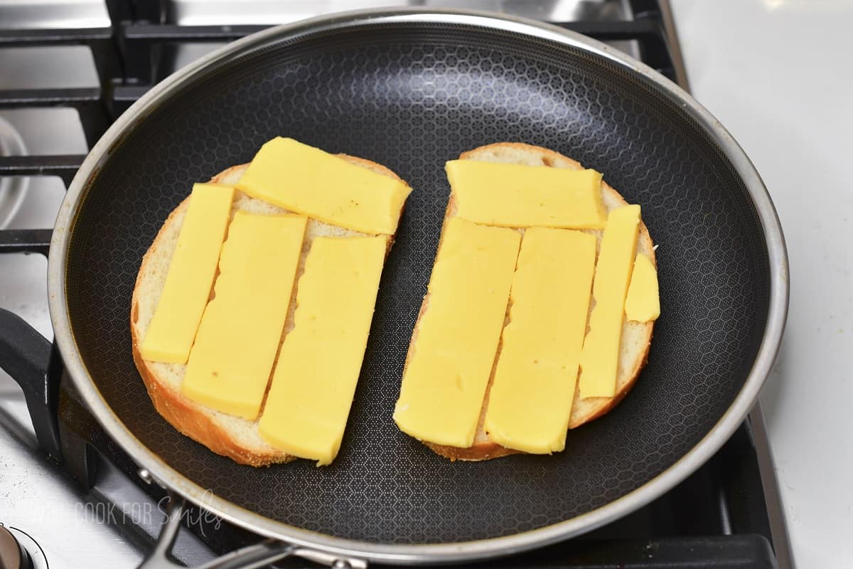 two slices of bread topped with Gouda cheese in the pan.