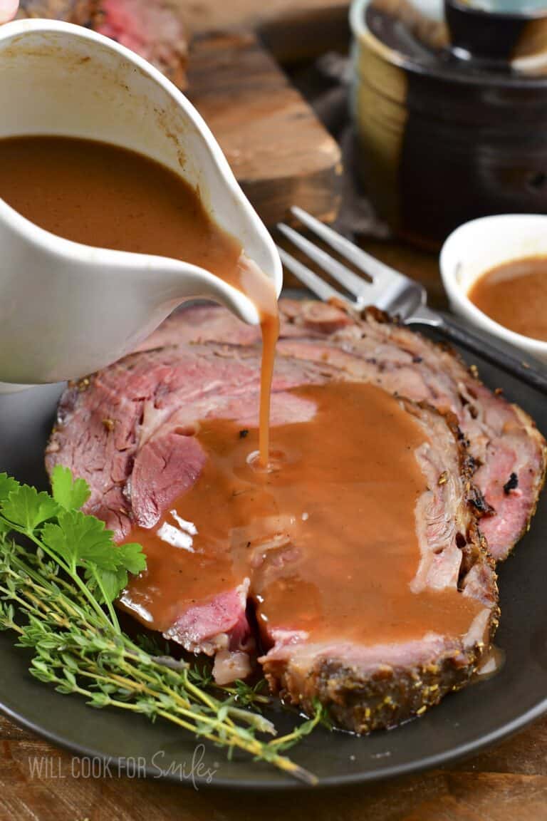 pouring au jus over the prime rib.