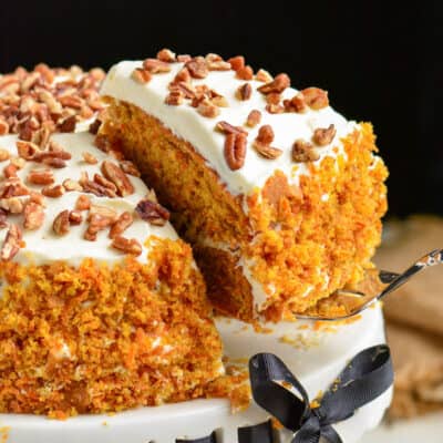 starting to take out a slice of carrot cake with a spatula.