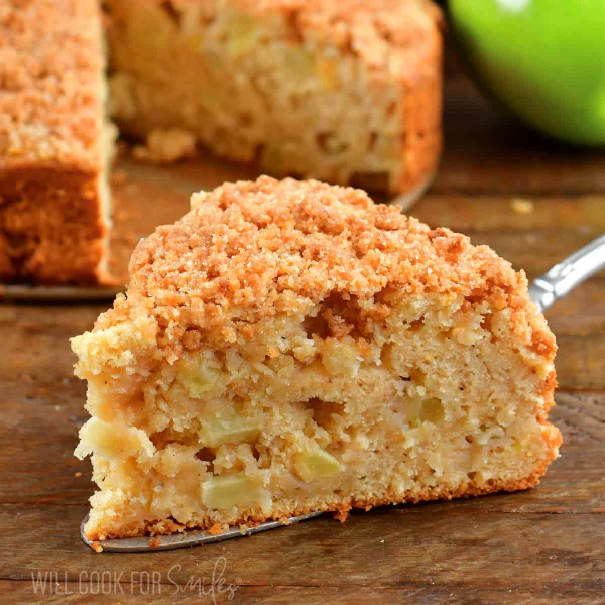 squared view of a slice of apple cake on silver spatula.