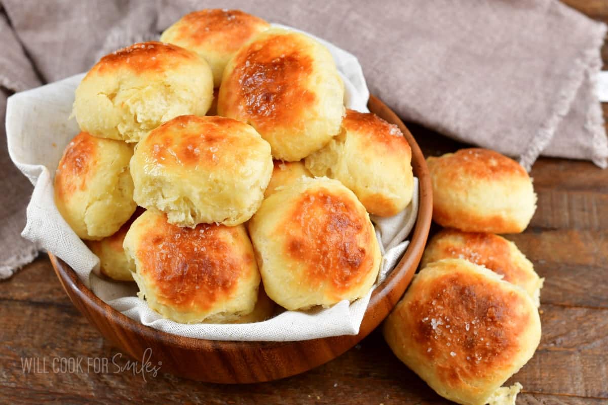 closeup of several potato rolls in a bowl with some around it.