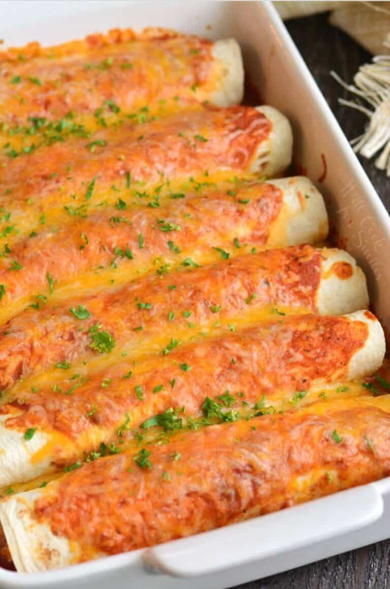 baked six chicken enchiladas in a white baking dish.