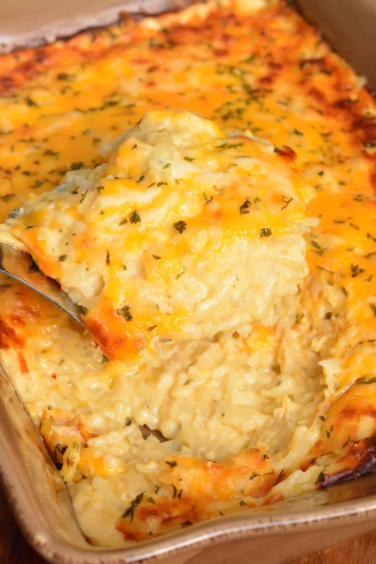 scooping out some hashbrown casserole with a silver spatula.