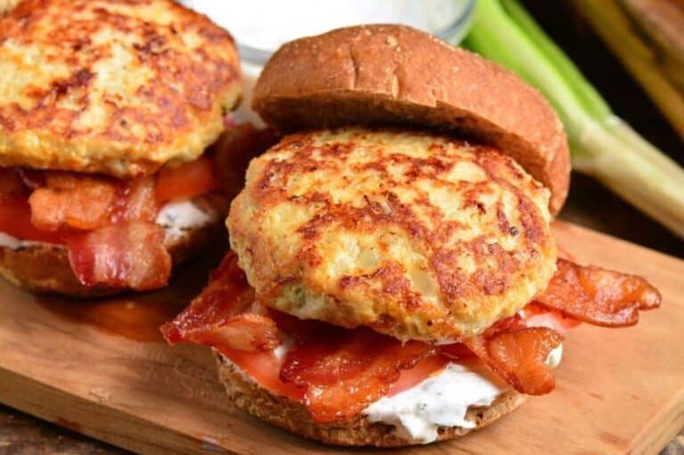 two cheddar ranch chicken burgers with bacon and sauce on a bun.