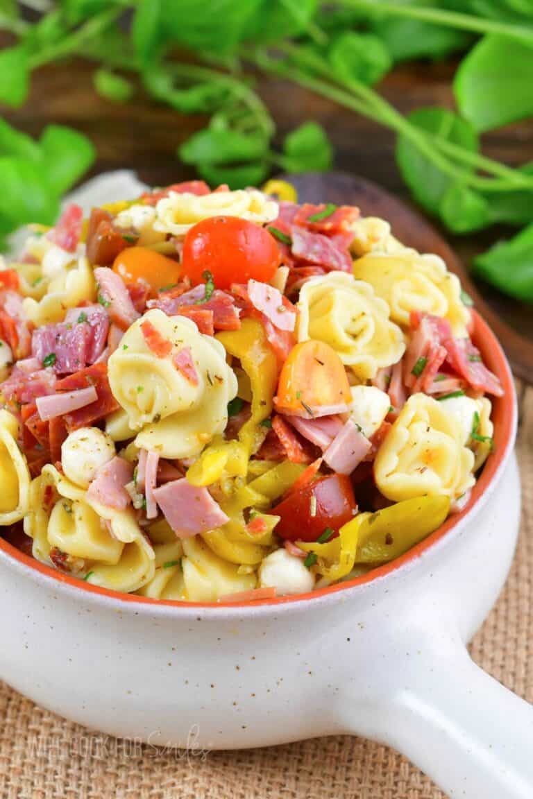 Italian tortellini salad filled in a light ceramic bowl with a handle.