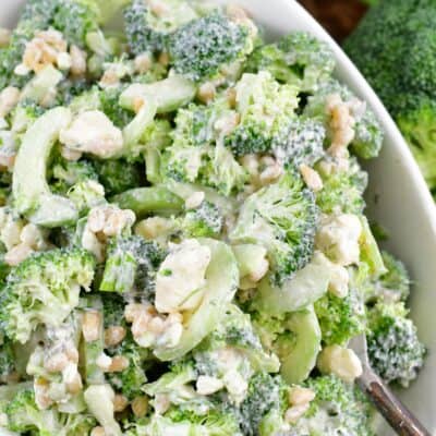 green broccoli salad with cucumber nuts and feta in a white bowl.