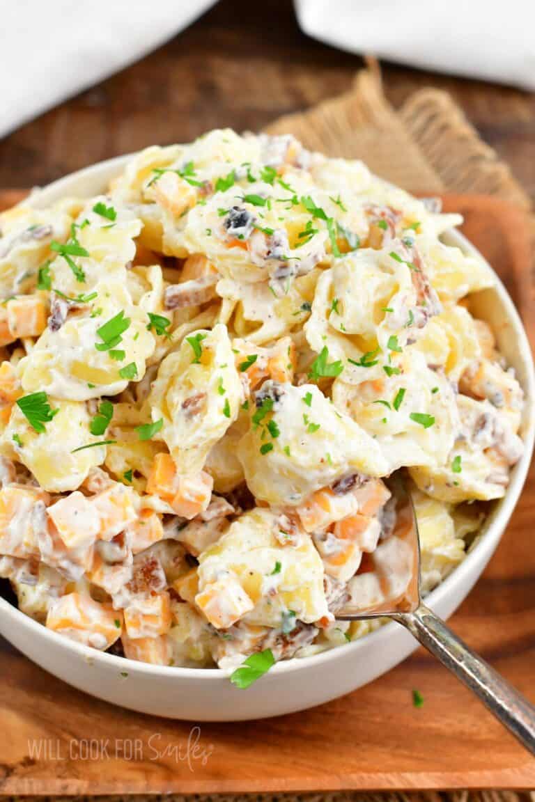 starting to scoop some creamy tortellini salad out of the bowl.