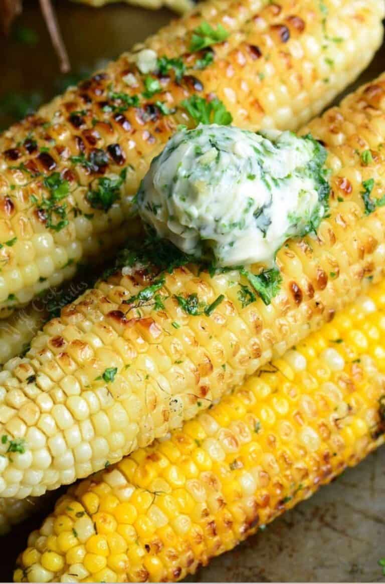 garlic herb butter is placed on top of grilled corn on the cob