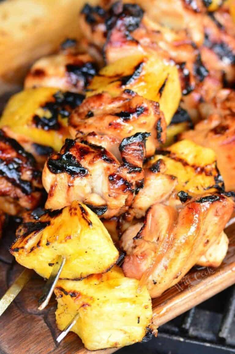 several pineapple chicken kebabs on skewers stacked on top of each other.