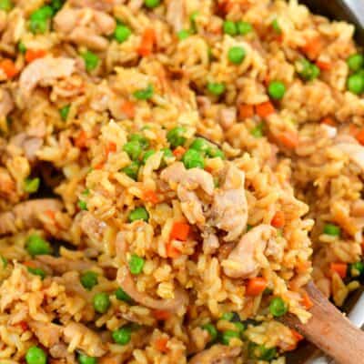 scooped out rice, chicken, and veggies on a wooden spoon over the pan.