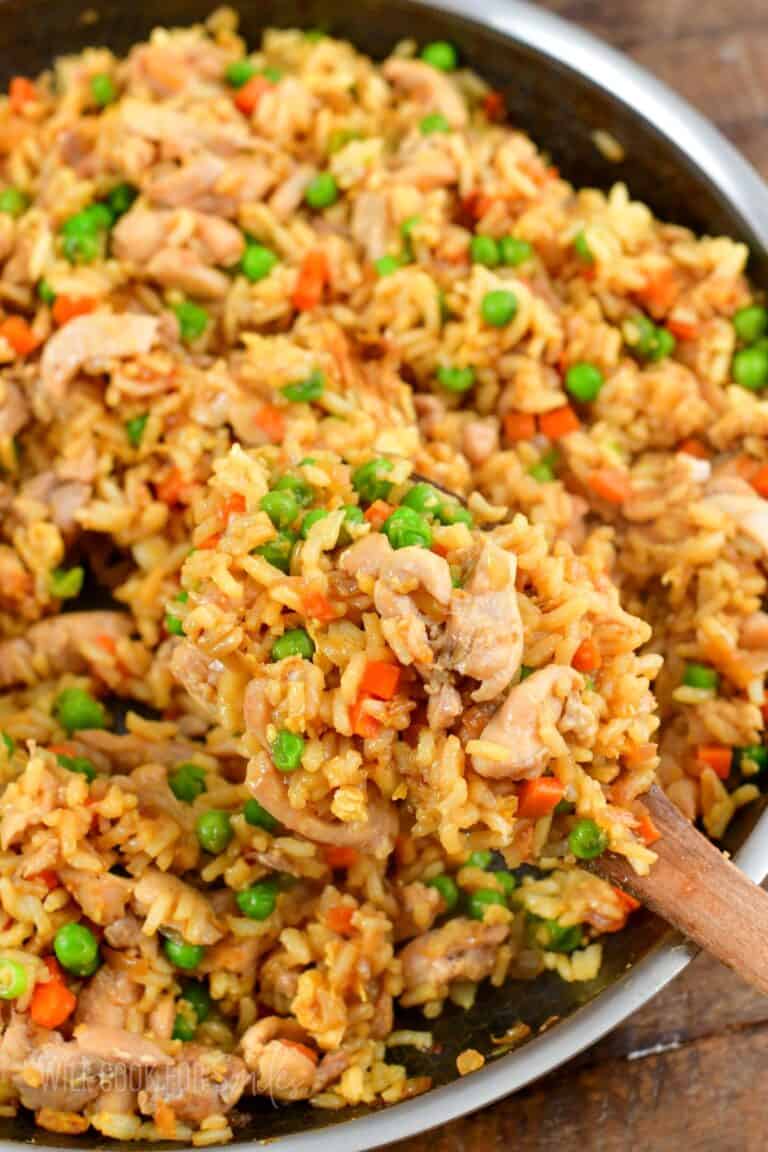 scooped out rice, chicken, and veggies on a wooden spoon over the pan.