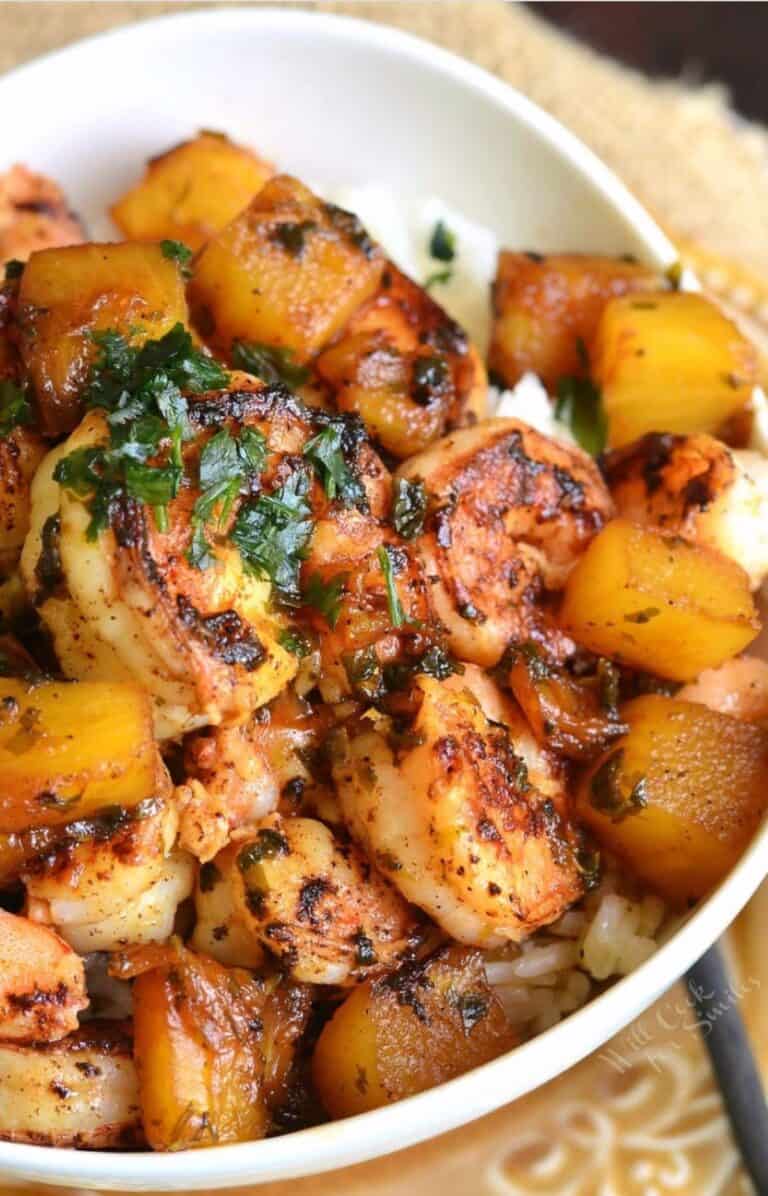 a white bowl filled with white rice and sauteed shrimp and pineapple over it.