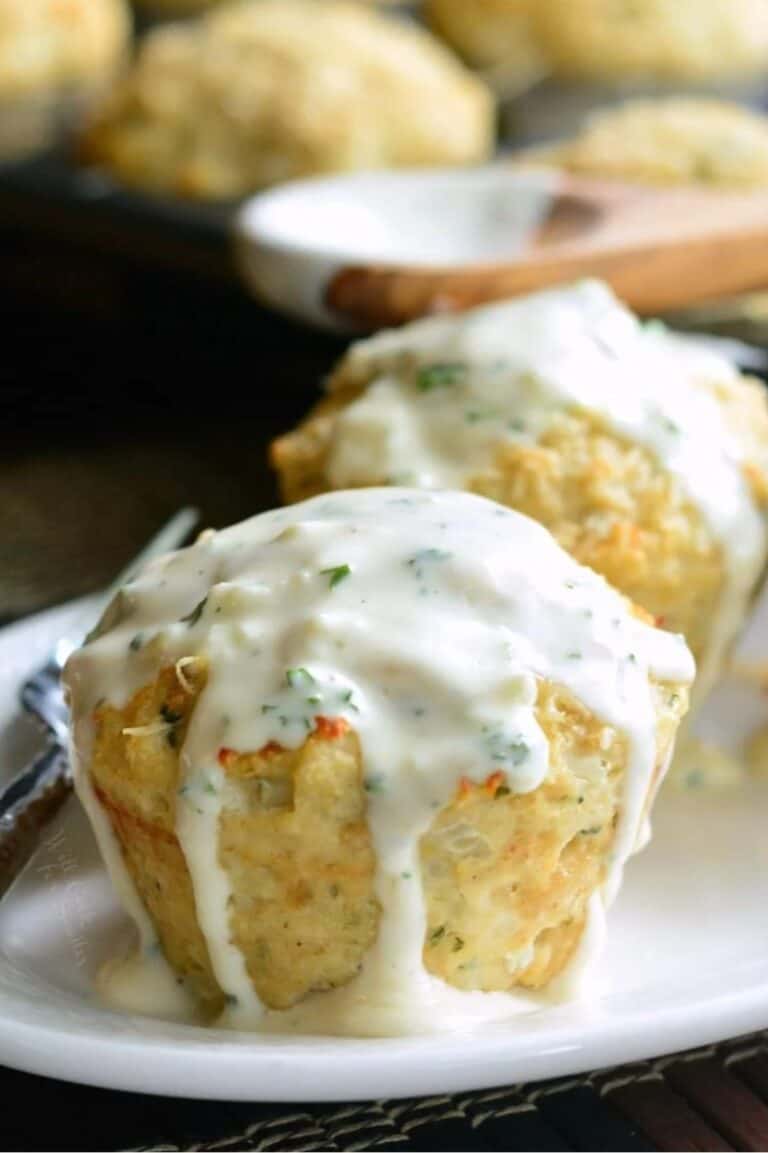 two garlic parmesan chicken meatloaves on a white plate with white sauce over them.