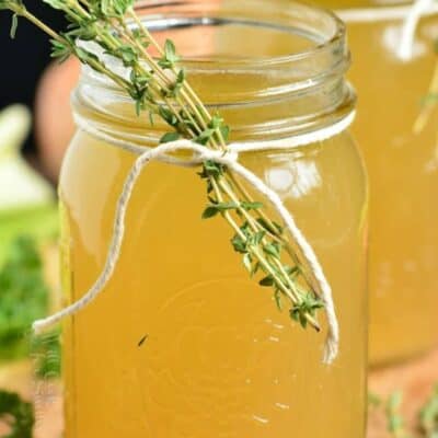 chicken stock in a mason jar with thyme tied to the jar with twine.