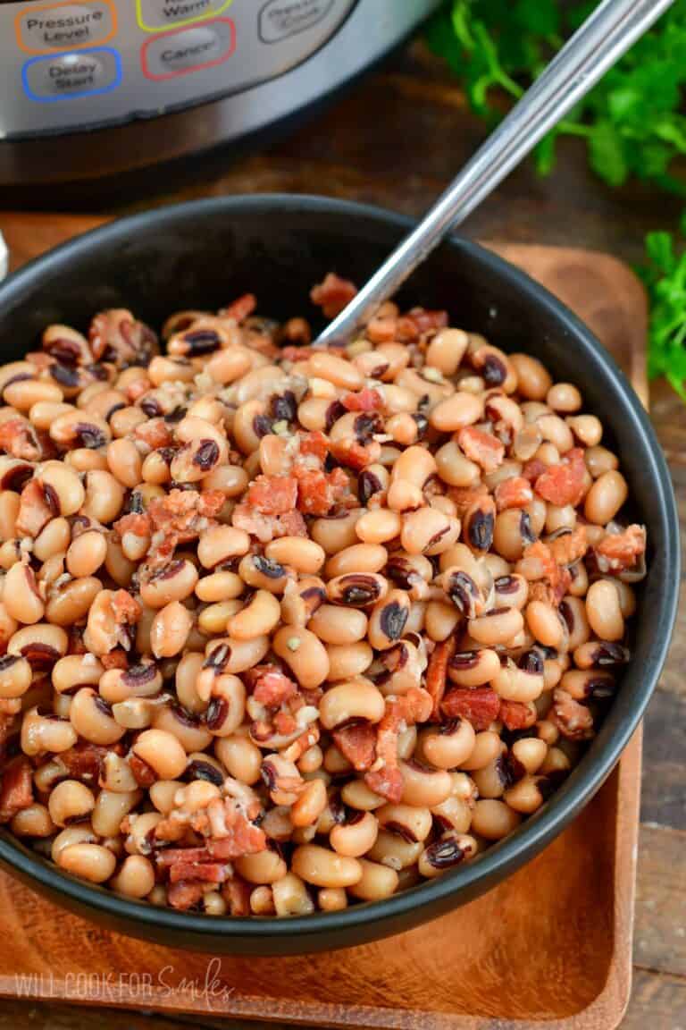 black eyed peas in a bowl with a fork in it on a wood surface.