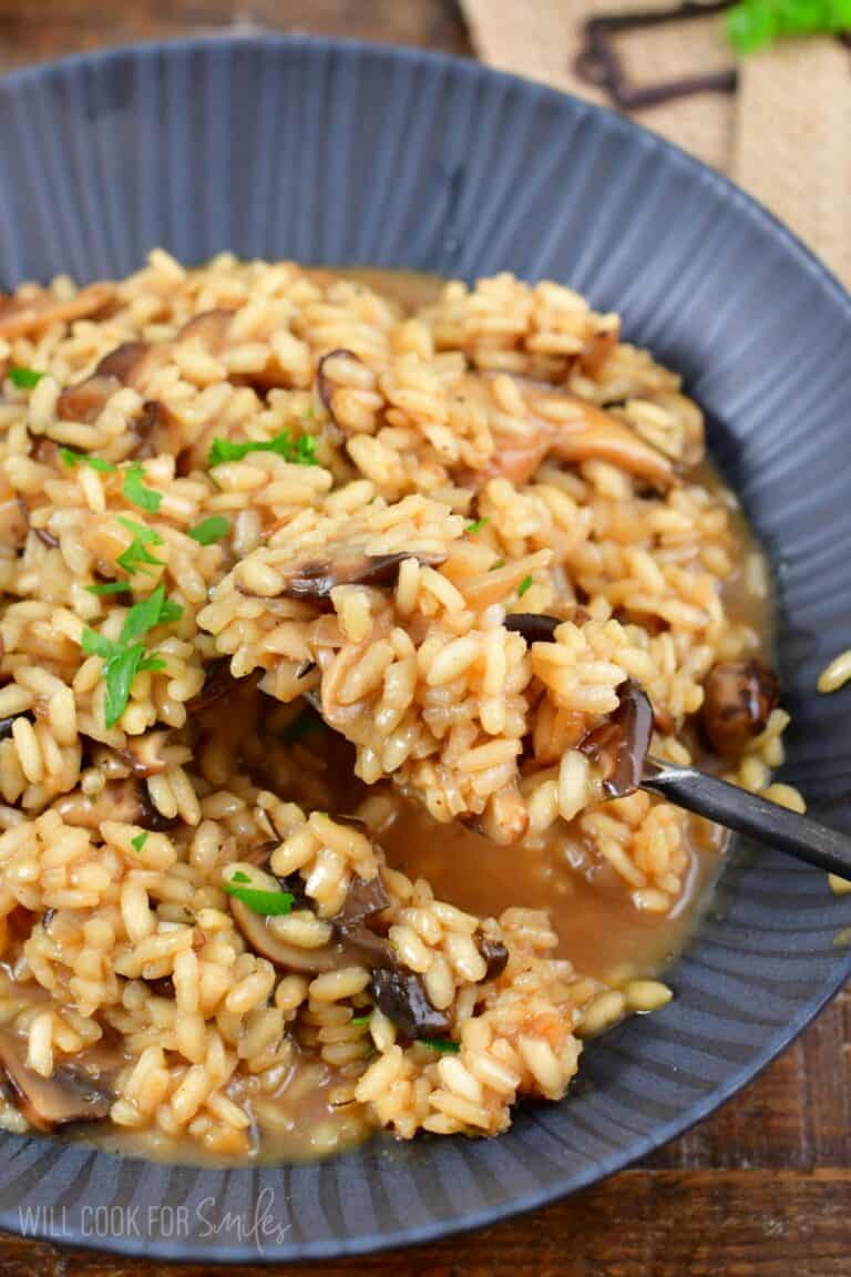 mushroom risotto in a bowl with a fork scooping it out.