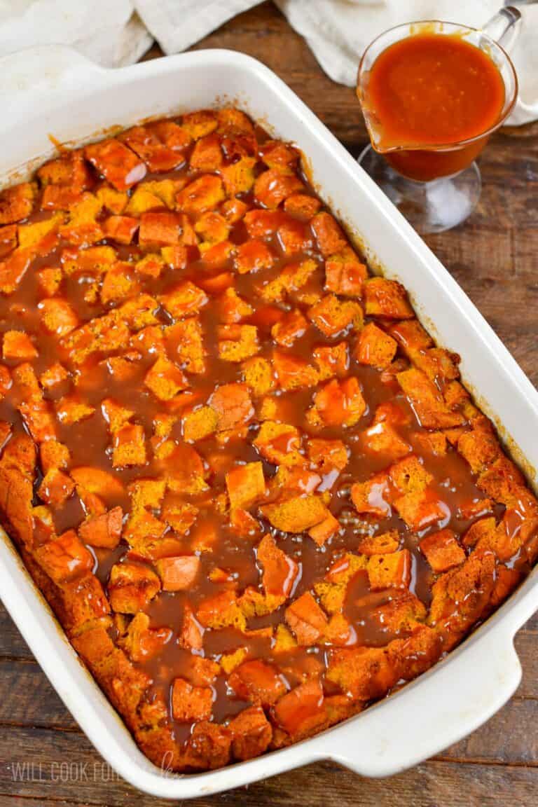 Pumpkin bread pudding with caramel over the top in a baking dish.