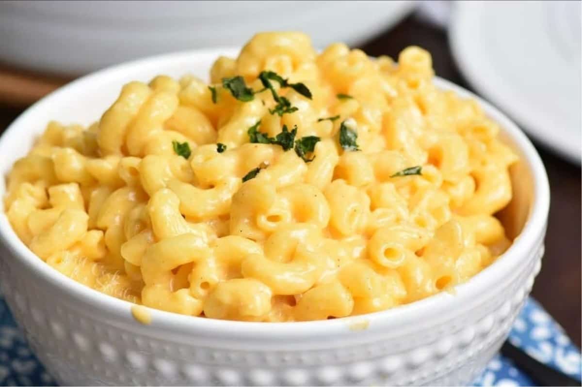 white bowl filled with creamy mac and cheese and topped with parsley.