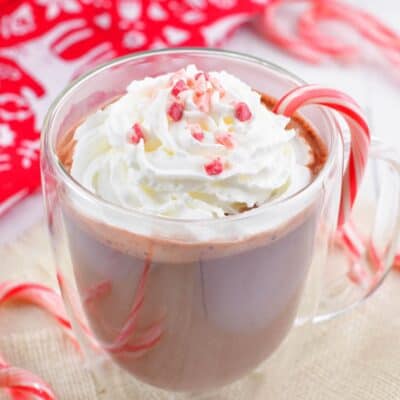 peppermint hot chocolate in a glass mug topped with whipped cream and peppermint crunch.