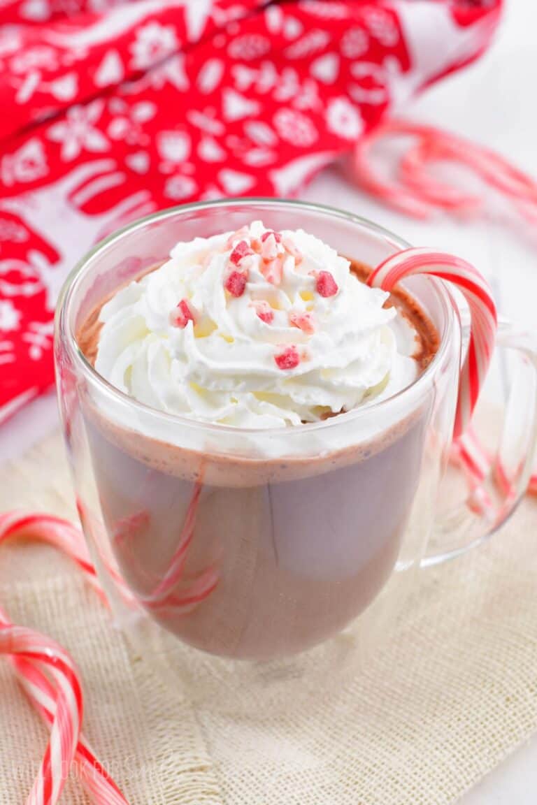 peppermint hot chocolate in a glass mug topped with whipped cream and peppermint crunch.