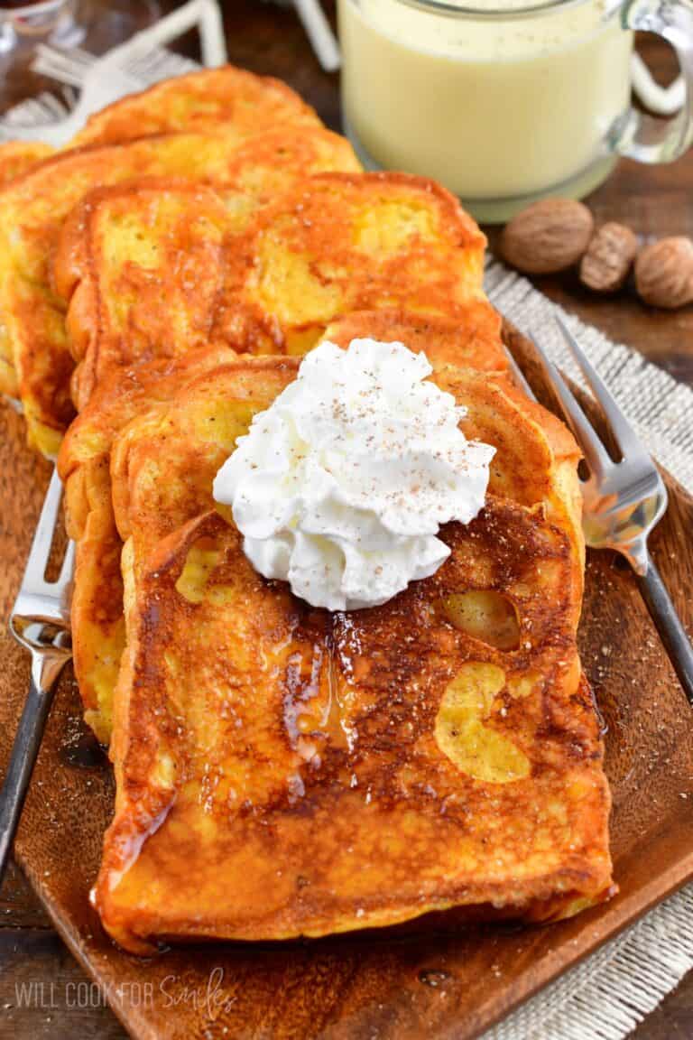 Eggnog French Toast on a plate with whipped cream on top.