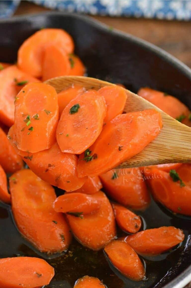 scooped honey glazed carrots on a wooden spoon over the skillet.