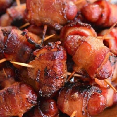 crispy bacon wrapped little smokies sausages on a wooden plate.