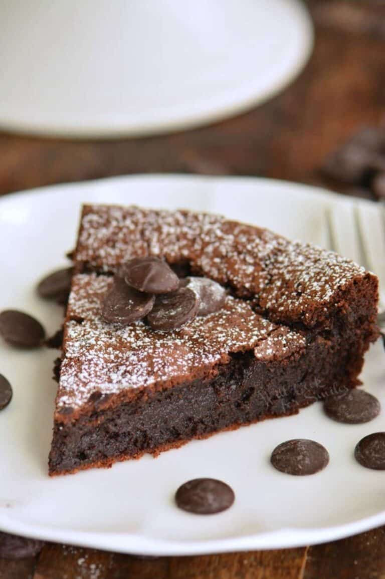 slice of flourless chocolate cake on the plate with some chocolate chips around.