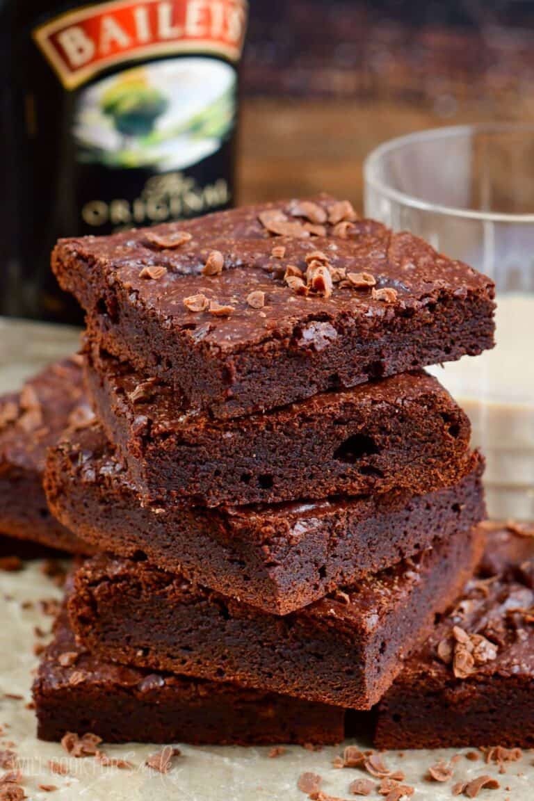 Brownies cut into squares and stacked on up on a piece of parchment.