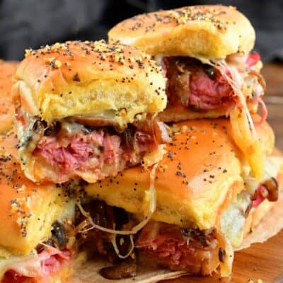 Two corned beef sliders stacked on top on a wood cutting board.