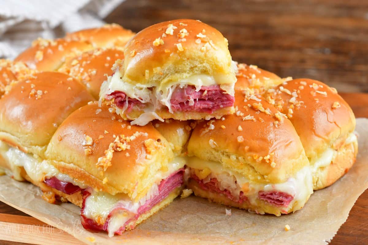 One reuben slider stacked on top of the rest of the sliders parchment paper.