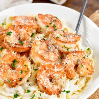 Shrimp alfredo in a white bowl on a burlap tablecloth.