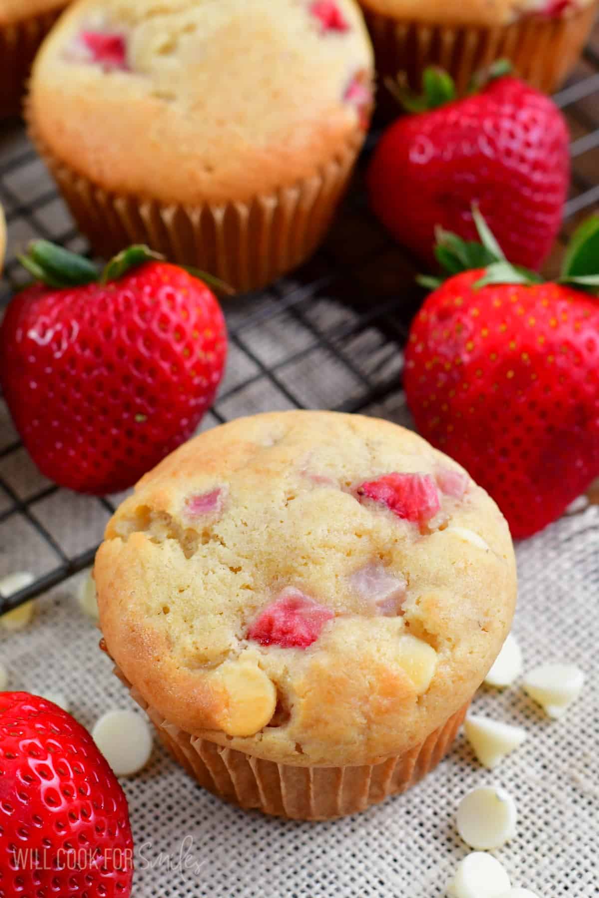 White chocolate chip strawberry muffins with white chocolate chips and strawberries around it.