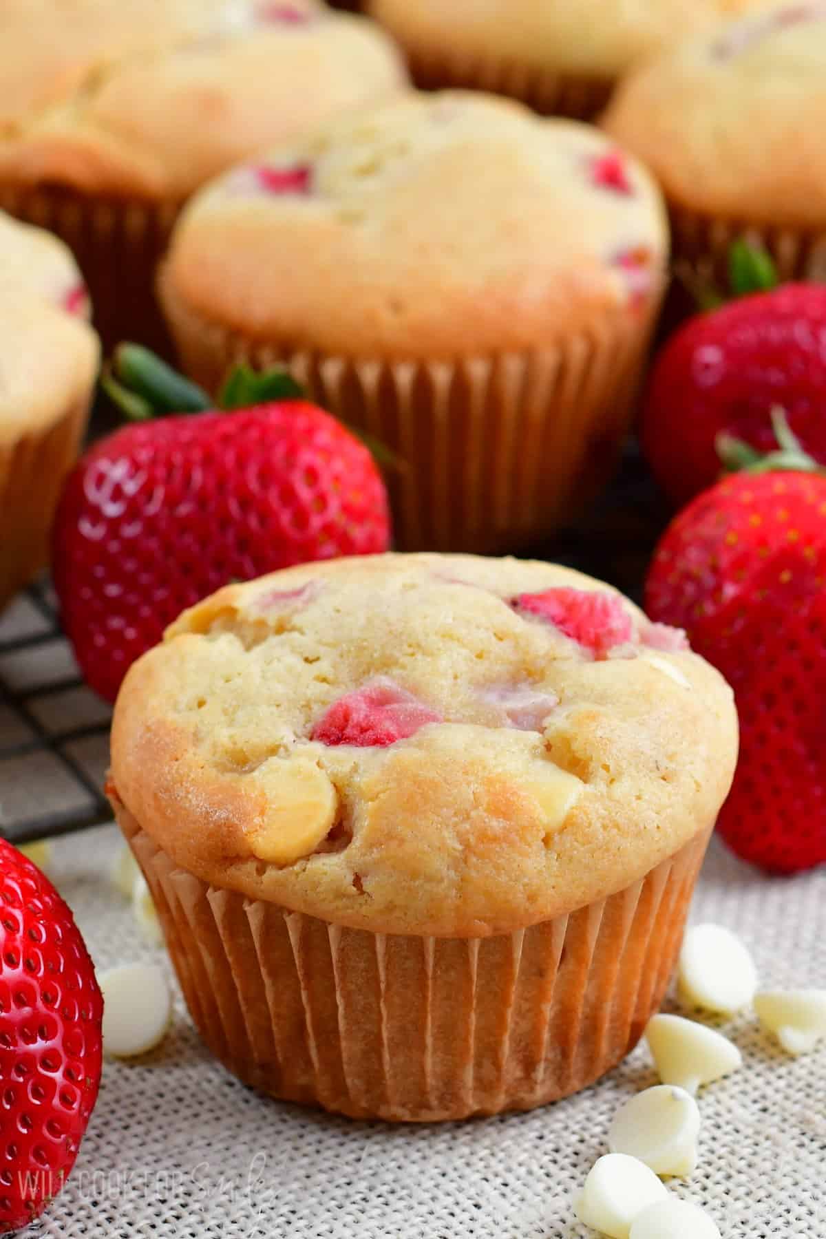 white chocolate muffin on table top with chocolate chips and strawberries around it.