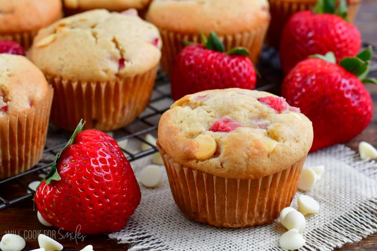 White Chocolate Chip Strawberry Muffins on a white napkin with a strawberry and white chocolate chips.