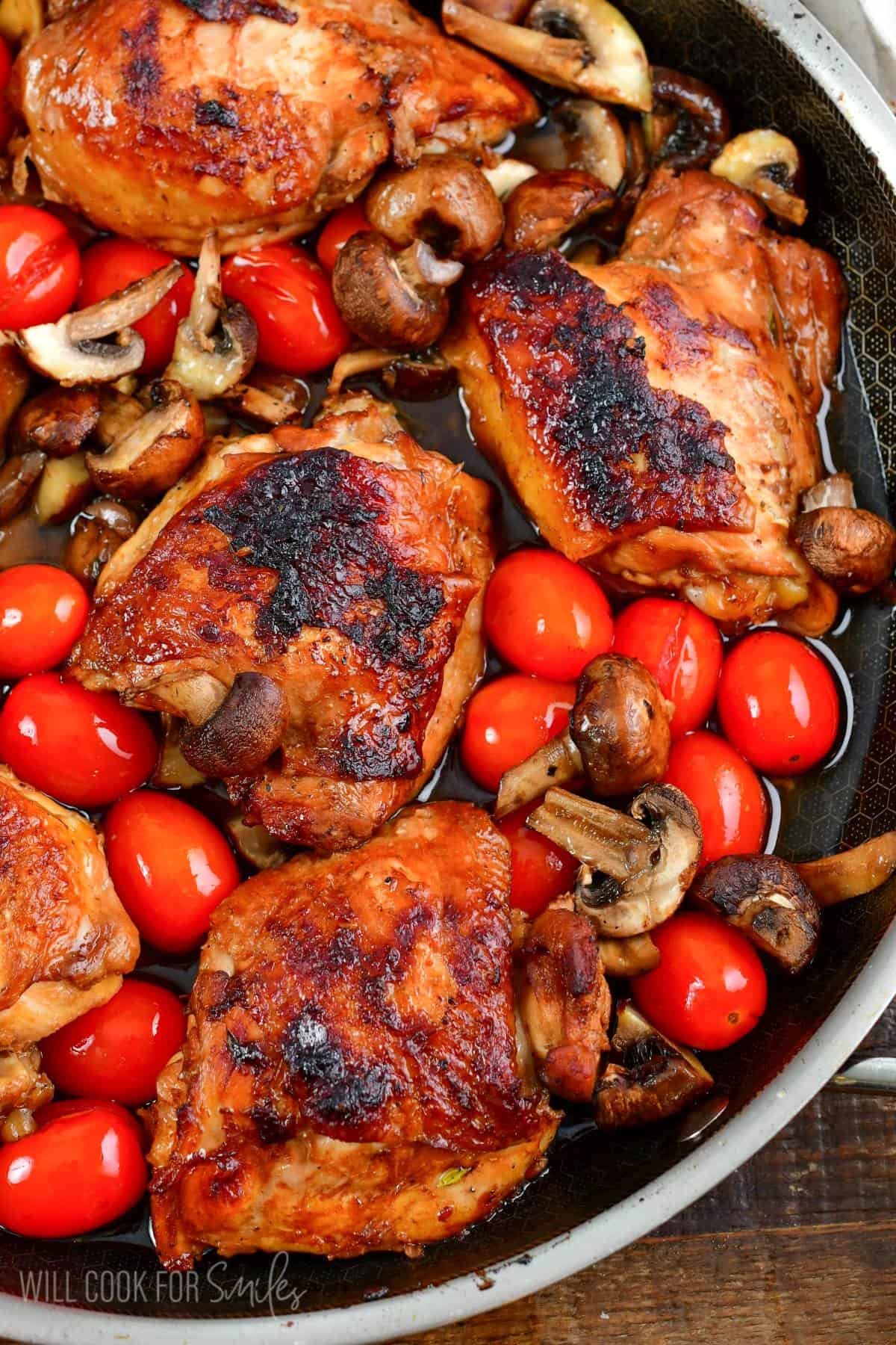 Chicken thighs in a pan baked with mushrooms and cherry tomatoes.