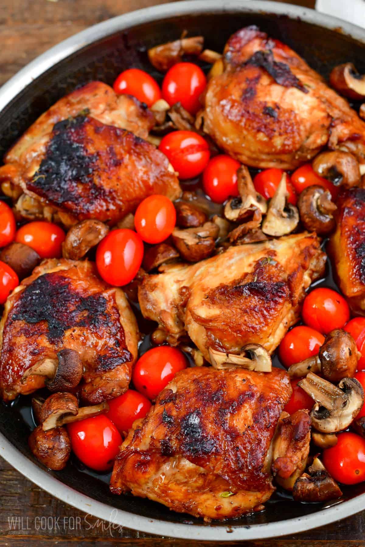 Balsamic Baked Chicken thighs with mushrooms and cherry tomatoes in a pan.