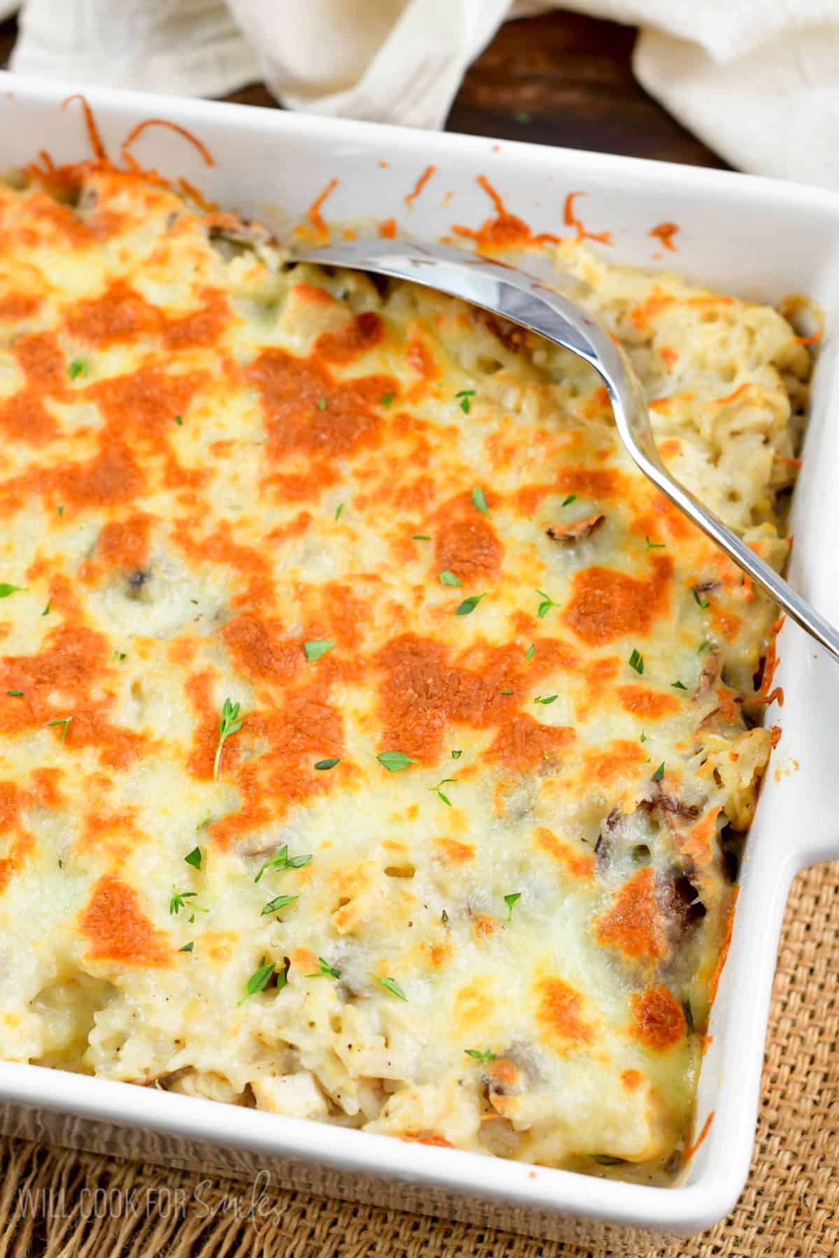 Creamy chicken rice casserole in a casserole dish with a big metal spoon.