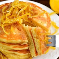 lemon Pancakes with a piece cut out and using a fork to pull it out.