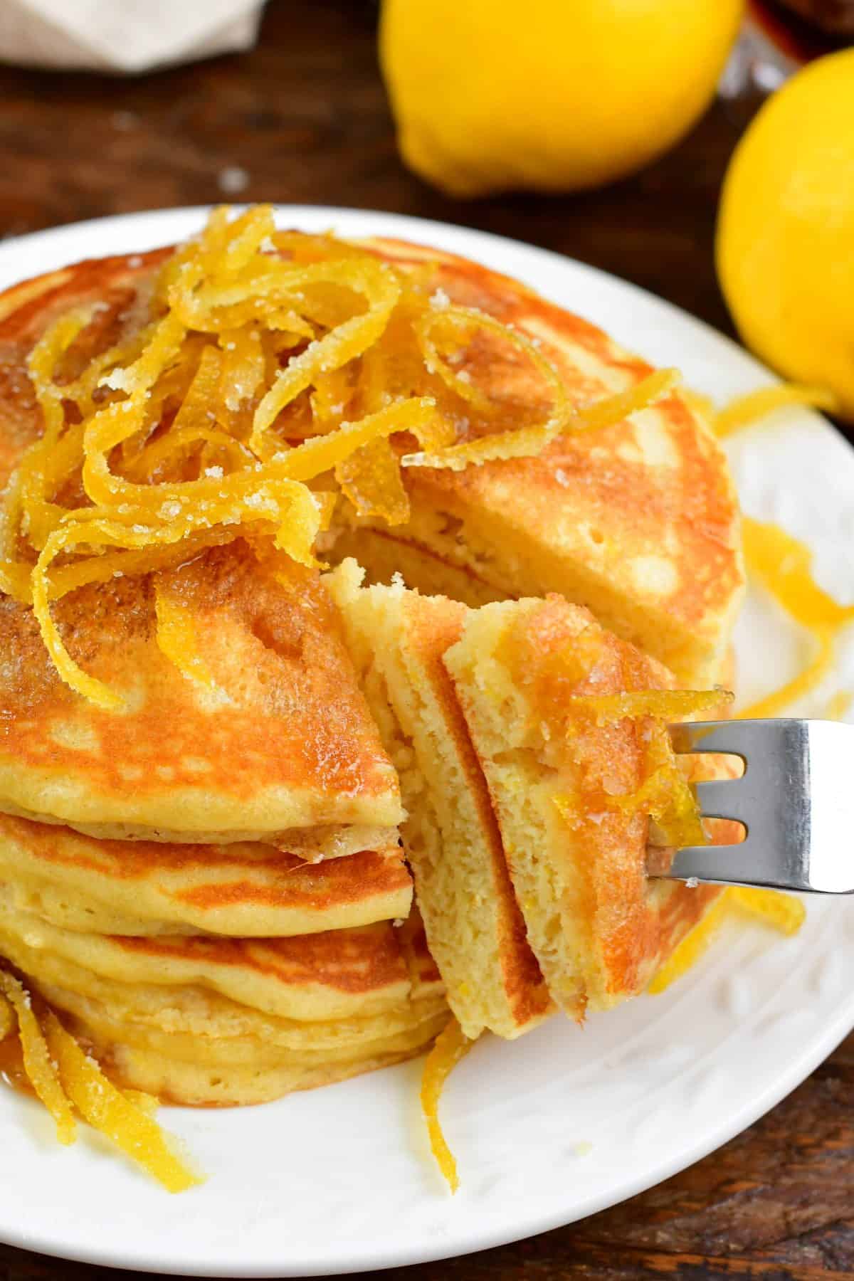 lemon Pancakes with a piece cut out and using a fork to pull it out.